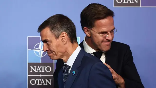 ルッテ氏の前を通り過ぎるサンチェス氏。2人はダークスーツ姿で、ルッテ氏はサンチェス氏の背中に手を添えている