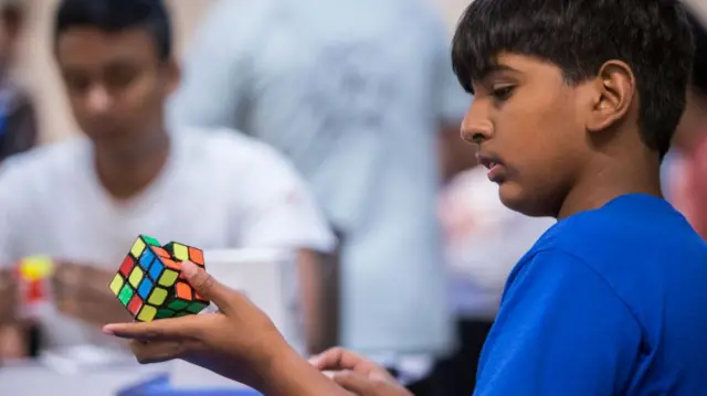 Menino brincando com cubo mágico