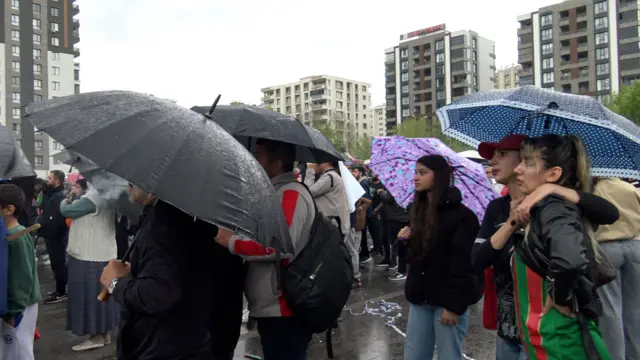 Sağanak yağmura rağmen şemsiyelerin altında maçı izleyen kadınlar