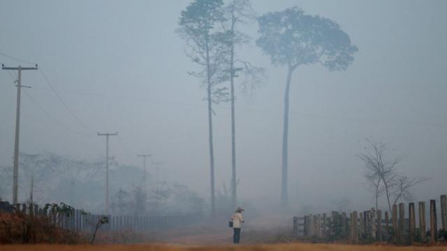 Homem caminha em estrada em Porto Velho em meio a fumaça