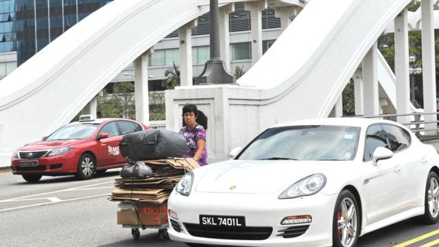 新加坡拾荒婦女推著車子走在繁忙的交通中