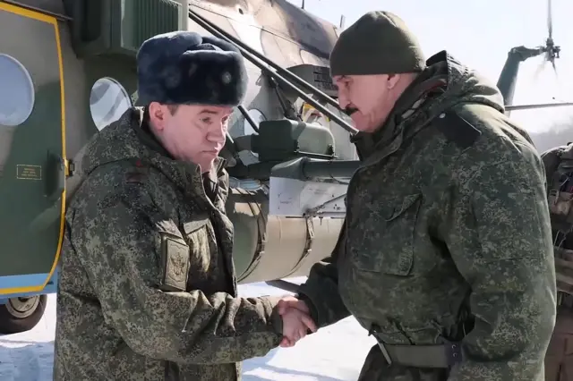 Герасимов в камуфляжной кукртке и меховой шапке пожимает руку Кузовлеву, который также в камуфляже и в вязаной зеленой шапочке
