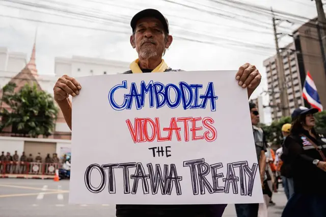 Một người biểu tình cầm biểu ngữ ghi dòng chữ "Campuchia vi phạm Hiệp ước Ottawa" trong một cuộc biểu tình phản đối căng thẳng tại biên giới Thái Lan-Campuchia, được chụp ngày 20/7 trước Đại sứ quán Hoàng gia Campuchia tại Bangkok