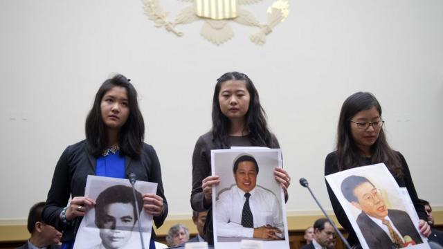彭明的女儿（图左）和王炳章的女儿（图右）在美国国会一个听聆会手持她们父亲的照片。