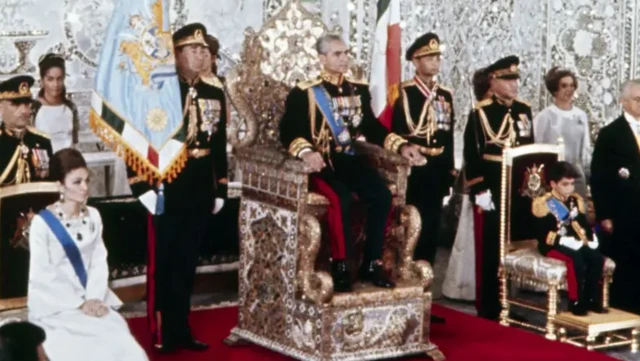 محمدرضا پهلوی در یک مراسم رسمی بر تخت سلطنت نشسته طرفین او فرح پهلوی، همسر او و پسرش رضا پهلوی در ایام کودکی نشسته‌اند. پشت سر او و اطرافش چند نیروی نظامی و افراد دیگر با لباس‌ رسمی دیده می‌شوند