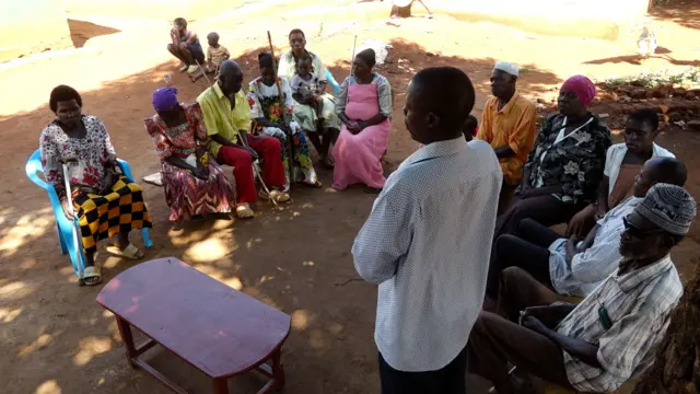 Moïse s'adressant à un groupe de membres de la communauté à l'ombre du jacquier qu'ils partagent.