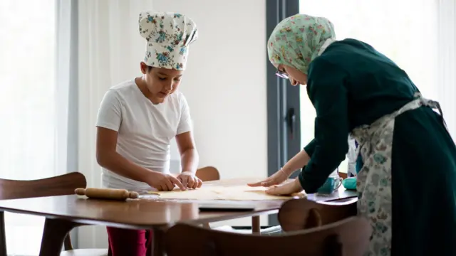 أم وطفلها يخبزان ويعدّان الطعام.