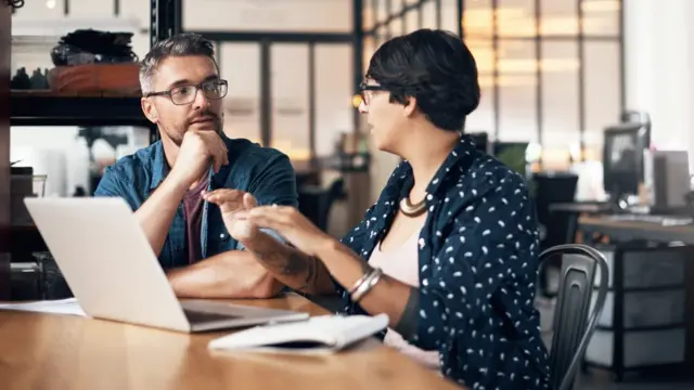 Dos personas hablando en un entorno laboral.