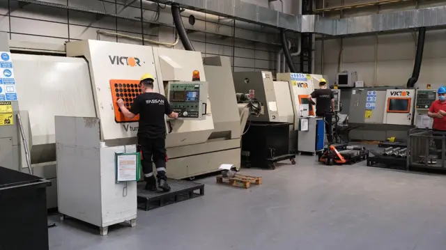 Assan yazılı üst giyinmiş iki çalışan Victor yazılı bir panelde tuşlara dokunuyor.