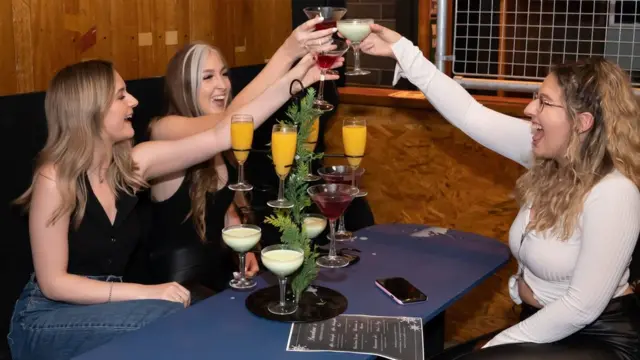 Left to right Rosie Delaney, Isobel Loan and Rebecca Mitchell get their first drink at 00:11 at the Showtime Bar in Huddersfield, West Yorkshire, as indoor hospitality and entertainment venues reopen to the public following the further easing of lockdown restrictions in England