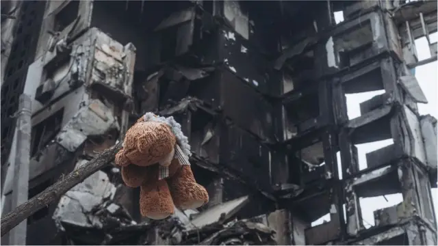 A teddy bear hanging from a tree in front of a building bombed by the Russian army in Borodyanka (Ukraine), 6 April 2022