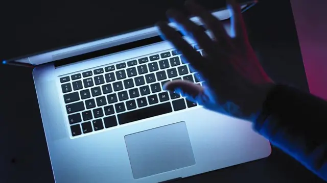 يد رجل تغلق اللابتوب، وتظهر لوحة المفاتيح في الصورة