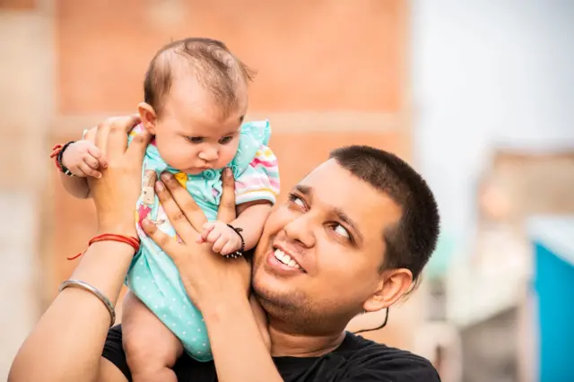 लहान बाळाला खेळवणारे वडील.