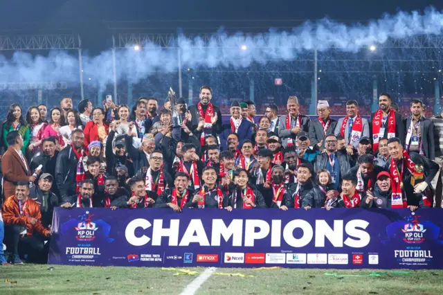 राष्ट्रिय युवा सङ्घ नेपालको आयोजनामा त्रिपुरेश्वरस्थित दशरथ रङ्गशालमा भएको ‘केपी ओली कप फुटबल च्याम्पिअन्शि'को फाइनल खेलमा विजयी मछिन्द्र फुटबल क्लबका खेलाडीहरूसँग बुफोन र प्रधानमन्त्री केपी शर्मा ओली 