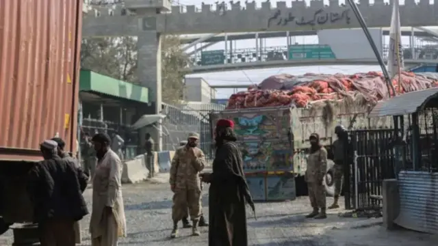 گذرگاه تورخم میان افغانستان و پاکستان، رانندگان، نیروهای امنتی و یک موتر پر از اموال در تصویر دیده می‌شود.