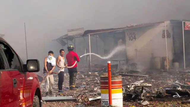 Pobladores locales y bomberos con mangueras.