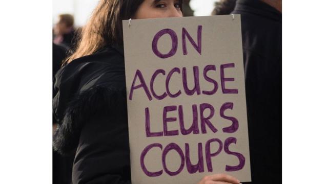 Une militante contre les violence faites aux femmes tenant un pancarte avec linscription " on accuse leurs coups"