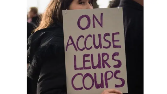 Une militante contre les violence faites aux femmes tenant un pancarte avec linscription " on accuse leurs coups"