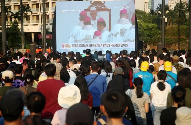Umat Katolik yang tidak bisa masuk ke dalam Stadion GBK mengikuti Misa Akbar dari videotron di luar stadion.