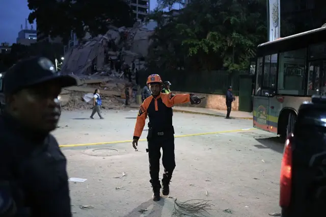 Un rescatista señalando hacia un lado, al frente de los escombros de un edificio colapsado en Caracas. 