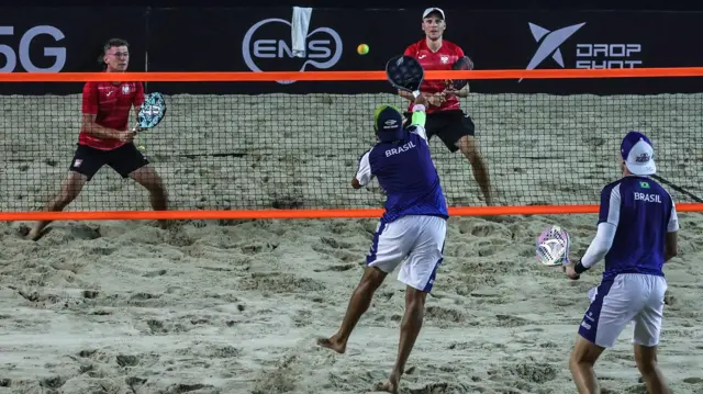 Quatro pessoas jogando beach tennis na Copa do Mundo 2022, duas delas com camisas do Brasil