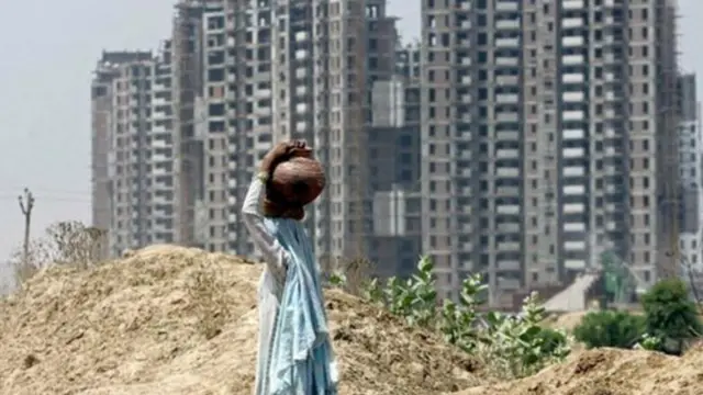 అపార్ట్‌మెంట్స్ వద్ద నీళ్లు తీసుకెళ్తున్న మహిళ