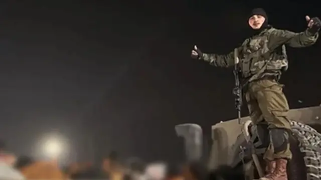 Askari wa IDF amesimama kwenye lori na wafungwa wakiwa wamefumba macho