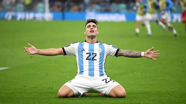 Lautaro Martinez is seen sliding on his knees with his arms out to celebrate Argentina's penalty shoot-out victory over the Netherlands in the quarter-finals of the 2022 Fifa World Cup