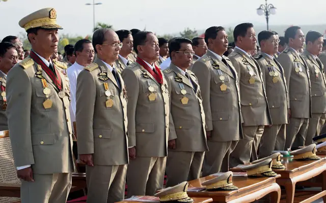 ပွဲတက်ယူနီဖောင်းဝတ်စုံအပြည့်ဝတ်ထားပြီး မတ်တပ်ရပ်နေတဲ့ ဗိုလ်ချုပ်ကြီး ၉ ဦးကို တပ်မတော်နေ့အခမ်းအနားမှာတွေ့ရစဥ်။