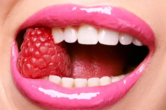 Boca mordiendo frambuesa