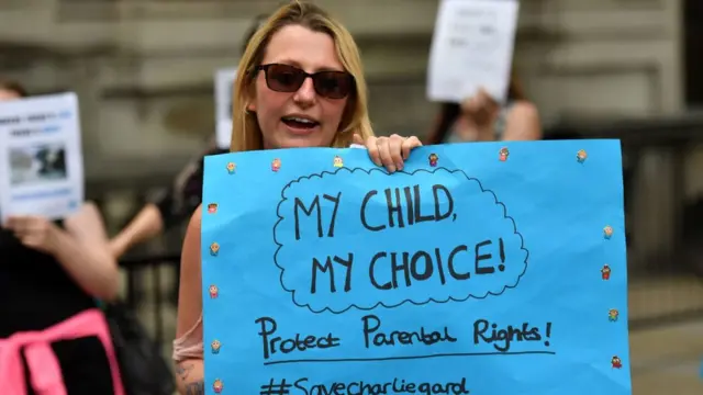 Женщина с плакатом в поддержку Чарли Гарда