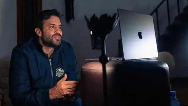 Marçal sorrindo em frente a laptop, aparentemente gravando live