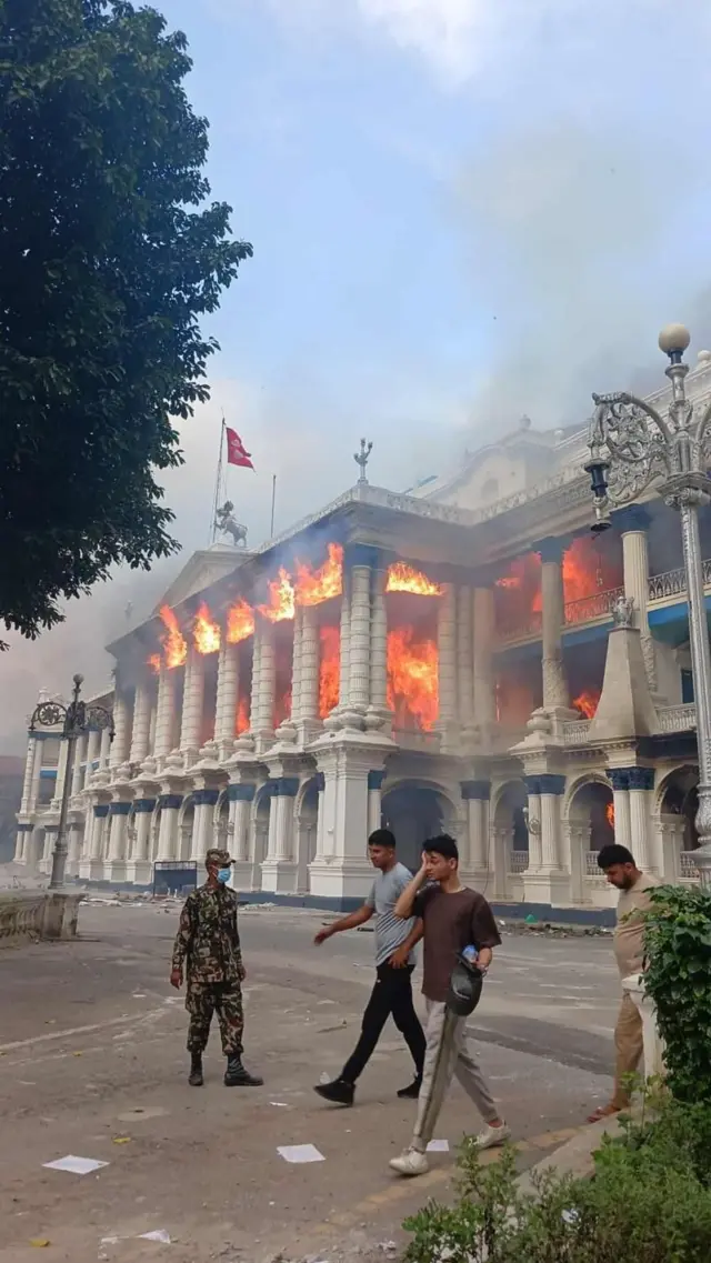 सिंहदरबारमा पुगेको क्षतिको आकलन गरिरहेको अधिकारीहरूले बताएका छन्। सिंहदरबारको अग्रभागमा आगो दन्किरहेको अवस्था। केही युवा र एक जना सैनिक मूल भवन बाहिरको सडकमा उभिएका छन्