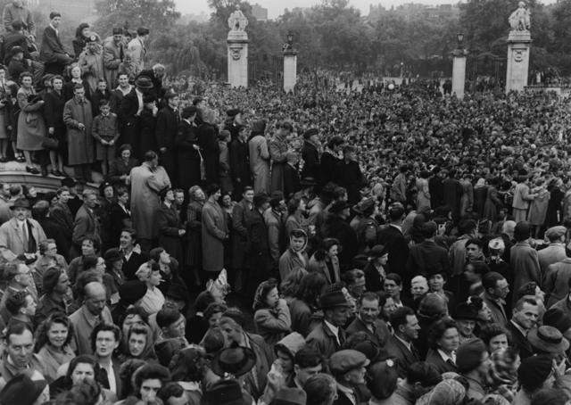 1945年8月15日，伦敦白金汉宫外人群聚集，等待国王乔治六世和王室成员出现，欢庆日本投降战事结束。