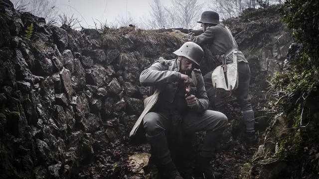 Soldado austrohúngaro en una trinchera encendiendo su pipa mientras otro hace guardia, otoño de 1916. Primera Guerra Mundial. Recreación histórica.