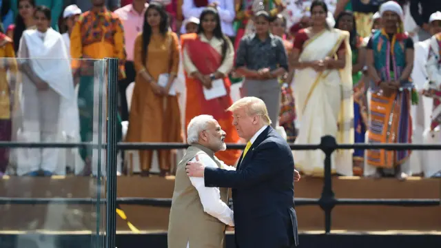 Моди и Трамп обнимаются на сцене индийского стадиона на фоне зрителей в национальных костюмах