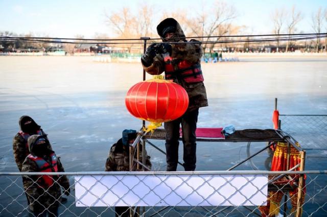 中国即将迎来春节。一名工作人员正在北京什刹海附近悬挂灯笼。