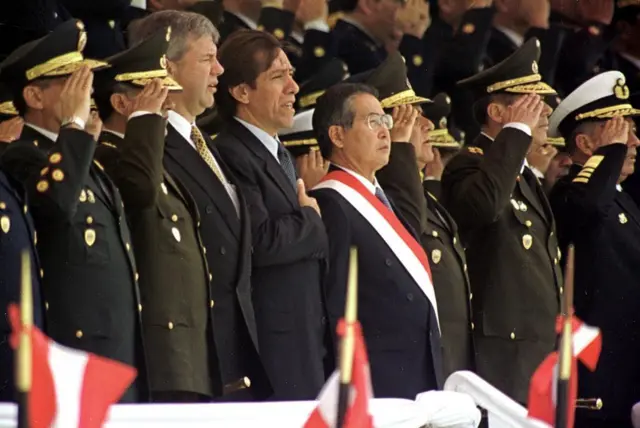 Alberto Fujimori, en pie y rodeado de militares en la tribuna de autoridades en un acto oficial cuando era presidente de Perú.