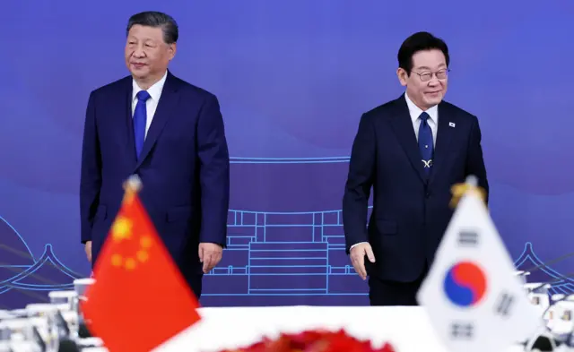 한국 경주에서 열린 회의에 참석한 시진핑 중국 국가주석과 이재명 한국 대통령. 앞에 양국 국기가 놓여있는 가운데 두 정상은 각자 다른 곳을 쳐다보고 있다