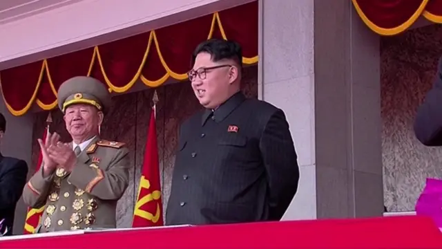 Kim Jong-un, smiling alongside a senior military official, on the podium above the event