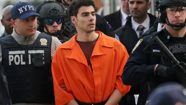 警官に囲まれ、オレンジ色の拘束服を着たマンジョーネ被告
