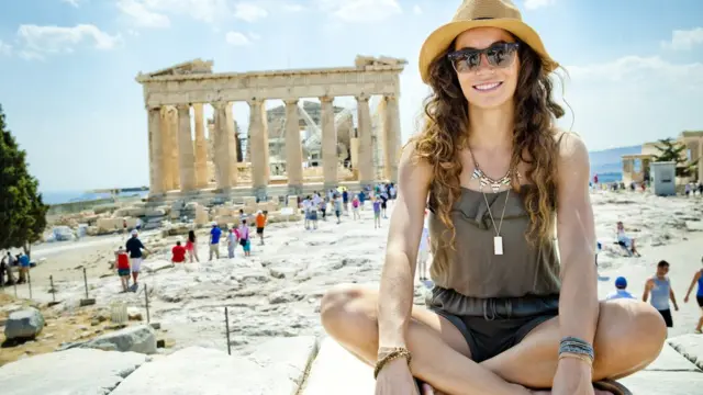 Una joven sentada frente al Partenón.