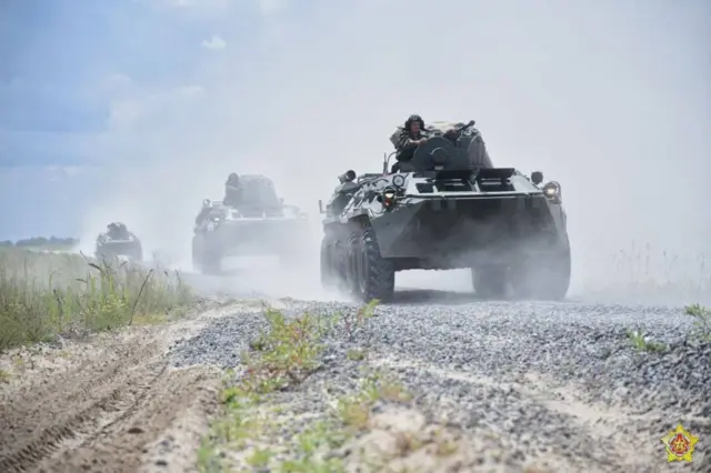 Три танки з військовими їдуть дорогою і здіймають пил
