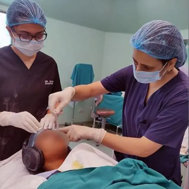 Dve medicinske sestre i jedna pacijentkinja na stolu sa slušalicama na ušima