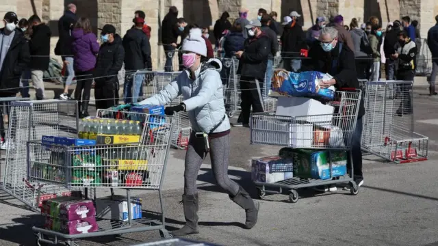Customers leave with supplies as others wait at the Costco Wholesale store in Austin, Texas, on 20 February 2021