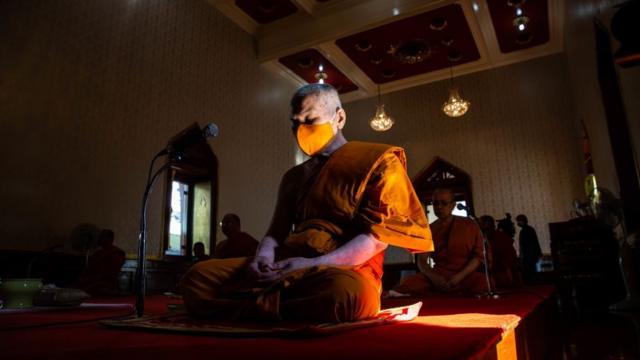 Tối trước hôm tình trạng khẩn cấp có hiệu lực, một vị sư đeo khẩu trang tụng kinh cầu nguyện cho Thái Lan chóng qua cơn dịch bệnh