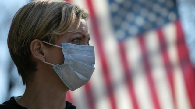 женщина в маске на фоне флага США