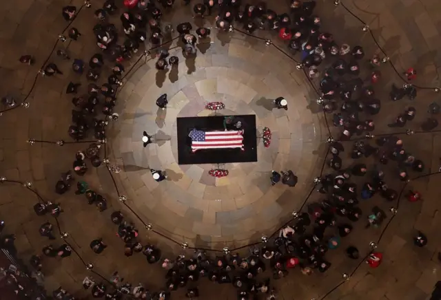 Former president George W. Bush and first lady Laura Bush put their hands on the casket of former president George H. W. Bush as he lies in state in the U.S. Capitol Rotunda