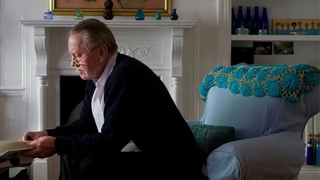 Chuck Feeney sentadoslotomania como jogarperfilslotomania como jogarsalaslotomania como jogarestar, olhando para livro