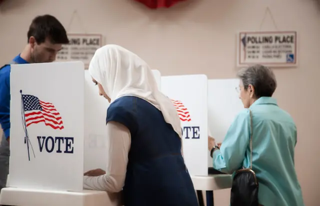 Mulher com véu muçulmano e idosa votandogates slotcabine